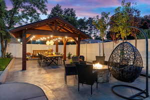 Patio terrace at dusk featuring a gazebo and an outdoor living space with a fire pit