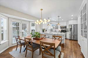 Dining space with sink, dark hardwood / wood-style flooring, and an inviting chandelier