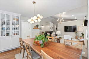 Dining area featuring hardwood / wood-style floors, lofted ceiling, and a notable chandelier