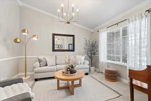 Living room featuring crown molding, light colored carpet, vaulted ceiling, and an inviting chandelier