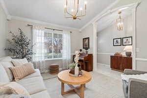 Living room featuring lofted ceiling, ornate columns, and crown molding