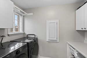 Washroom featuring washing machine and dryer and cabinets