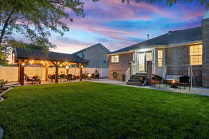 Back house at dusk featuring a yard and a patio area