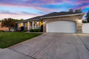 Single story home featuring a lawn, a porch, and a garage