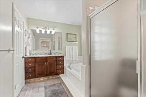 Bathroom featuring tasteful backsplash, tile patterned flooring, separate shower and tub, a textured ceiling, and vanity