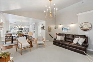 Carpeted living room featuring a chandelier and vaulted ceiling