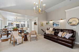 Living room with light carpet, sink, a chandelier, and lofted ceiling