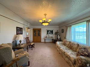 Carpeted living room featuring a textured ceiling and an inviting chandelier