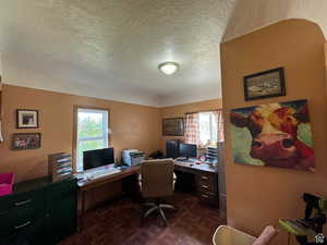 Home office featuring a textured ceiling, dark parquet floors, and plenty of natural light