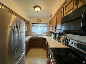 Kitchen with a textured ceiling, sink, and stainless steel appliances