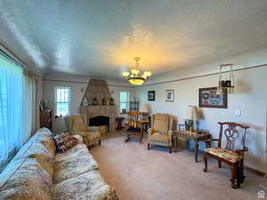 Living room featuring a chandelier, a textured ceiling, a fireplace, and carpet flooring