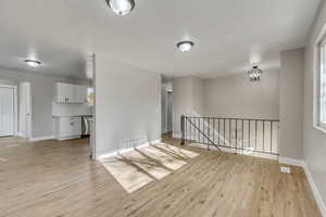 Empty room with light hardwood / wood-style flooring and an inviting chandelier