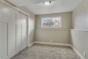 Unfurnished bedroom with light carpet and a closet