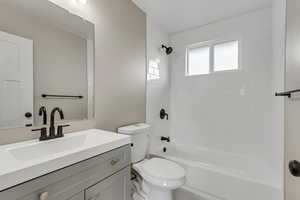 Full bathroom with vanity, tiled shower / bath combo, and toilet