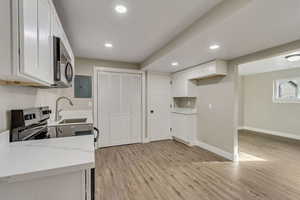 Kitchen with white cabinets, light hardwood / wood-style floors, and sink