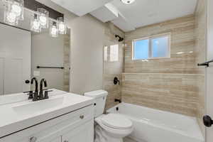 Full bathroom with toilet, vanity, and tiled shower / bath