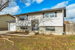 Bi-level home with a front yard and a garage