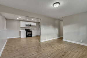 Unfurnished living room featuring light hardwood / wood-style floors and sink