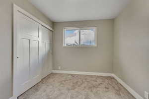 Unfurnished bedroom featuring light carpet and a closet