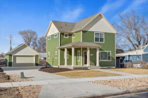 Victorian home featuring a garage, covered porch, and an outdoor structure