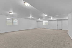 Basement with light colored carpet and a textured ceiling