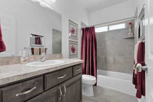 Full bathroom with tile patterned flooring, vanity, toilet, and shower / bath combo with shower curtain