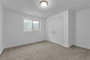 Unfurnished bedroom featuring carpet flooring, a textured ceiling, and a closet