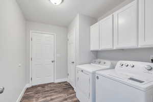 Clothes washing area with a textured ceiling, cabinets, independent washer and dryer, and dark wood-type flooring