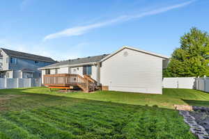 Back of house featuring a lawn and a wooden deck