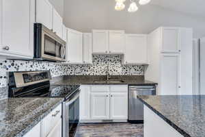 Kitchen featuring decorative backsplash, white cabinetry, sink, and stainless steel appliances