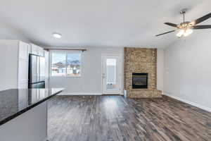 Unfurnished living room with ceiling fan, dark hardwood / wood-style floors, and a brick fireplace