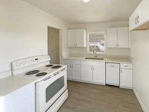 Kitchen with white cabinetry, light wood-type flooring, white appliances, and sink