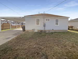 Back of property with a carport and a lawn