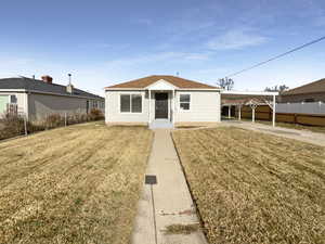 View of front of property featuring a front lawn and a carport