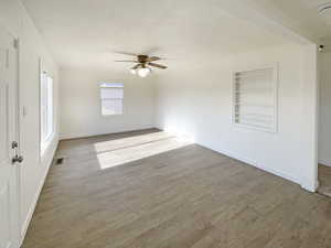 Spare room with built in shelves, a textured ceiling, light hardwood / wood-style floors, and ceiling fan