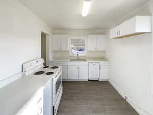 Kitchen featuring white cabinets, white appliances, dark hardwood / wood-style floors, and sink