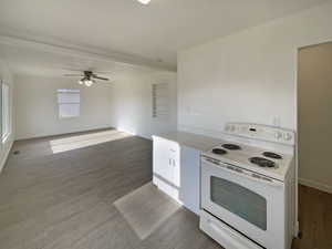 Kitchen featuring hardwood / wood-style floors, white electric range oven, ceiling fan, and white cabinetry