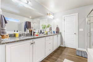 Bathroom featuring hardwood / wood-style flooring, vanity, and a shower with shower door