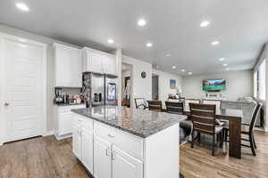 Kitchen featuring light hardwood / wood-style floors, a kitchen island, white cabinetry, and stainless steel refrigerator with ice dispenser