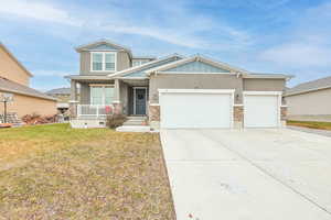 View of front of house with a porch, a garage, and a front lawn