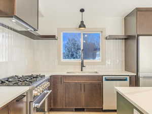 Kitchen featuring pendant lighting, decorative backsplash, sink, and stainless steel appliances