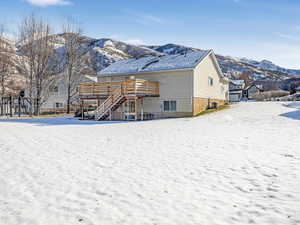 Snow covered house with a deck with mountain view