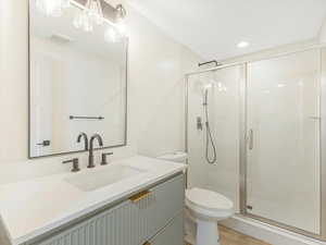 Bathroom with hardwood / wood-style flooring, vanity, toilet, and a shower with shower door