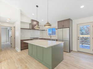 Kitchen featuring light stone countertops, sink, hanging light fixtures, stainless steel appliances, and a kitchen island