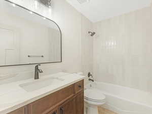 Full bathroom featuring toilet, vanity, hardwood / wood-style flooring, and bathing tub / shower combination