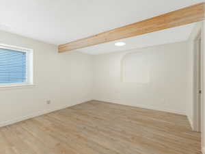 Unfurnished room featuring beam ceiling and light wood-type flooring