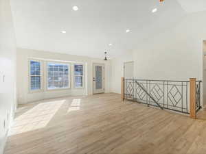 Unfurnished room featuring light hardwood / wood-style floors and lofted ceiling