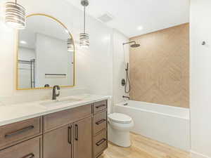 Full bathroom with bathtub / shower combination, hardwood / wood-style floors, vanity, and toilet