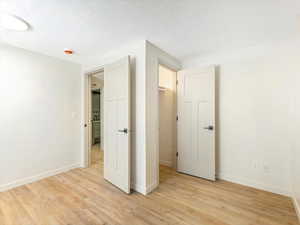 Unfurnished bedroom with a textured ceiling and light hardwood / wood-style floors