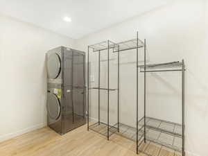 Washroom featuring hardwood / wood-style floors and stacked washer and clothes dryer